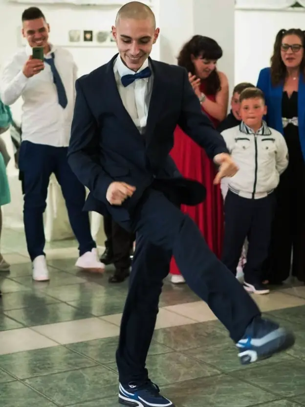 Ninho in a suit and bow tie, hakken at a wedding, one leg swung across the floor